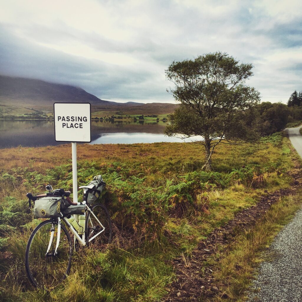 My bike leaning on a ‘Passing Pace’ sign in front of Loch Naver