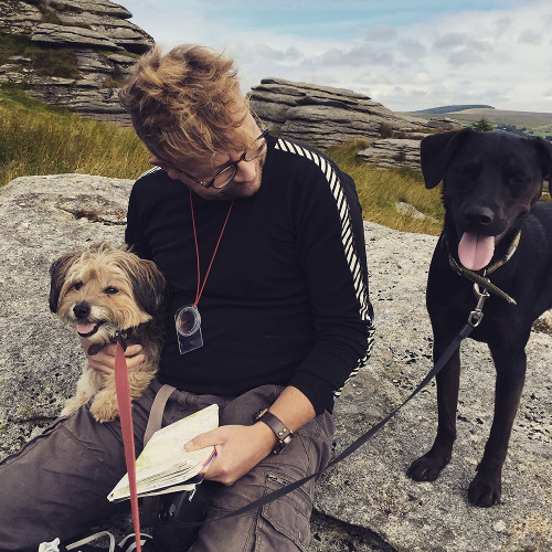 Richard sitting with two of his dogs on a Dartmoor rock